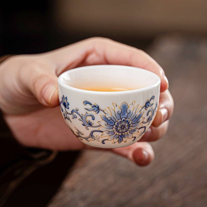 Close-up of a blue lotus porcelain teacup from a Gongfu Chinese tea set being held with tea