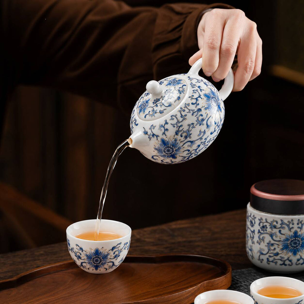 Blue lotus porcelain Gongfu teapot pouring tea into a teacup during a traditional Chinese tea ceremony