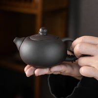Handheld purple clay teapot with a smooth matte finish from a portable Chinese tea set