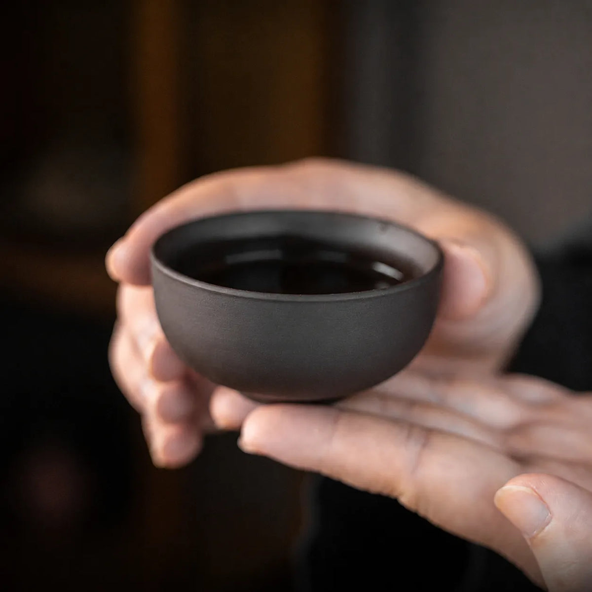 Close-up of a small purple clay tea cup from a portable Chinese tea set